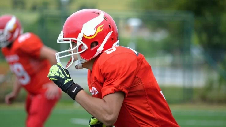 Two young men in red uniforms playing football