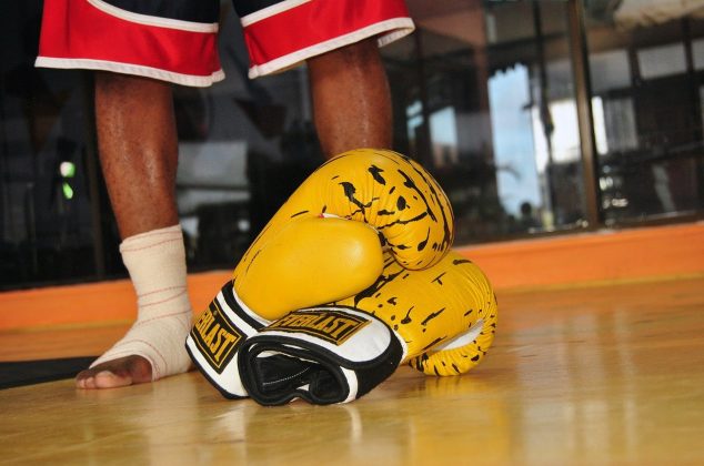 Yellow boxing gloves resting in front of boxer's feet