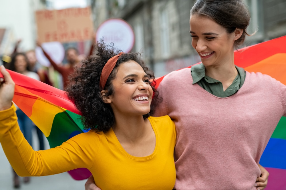 LGBTQ group members marching with a rainbow flag