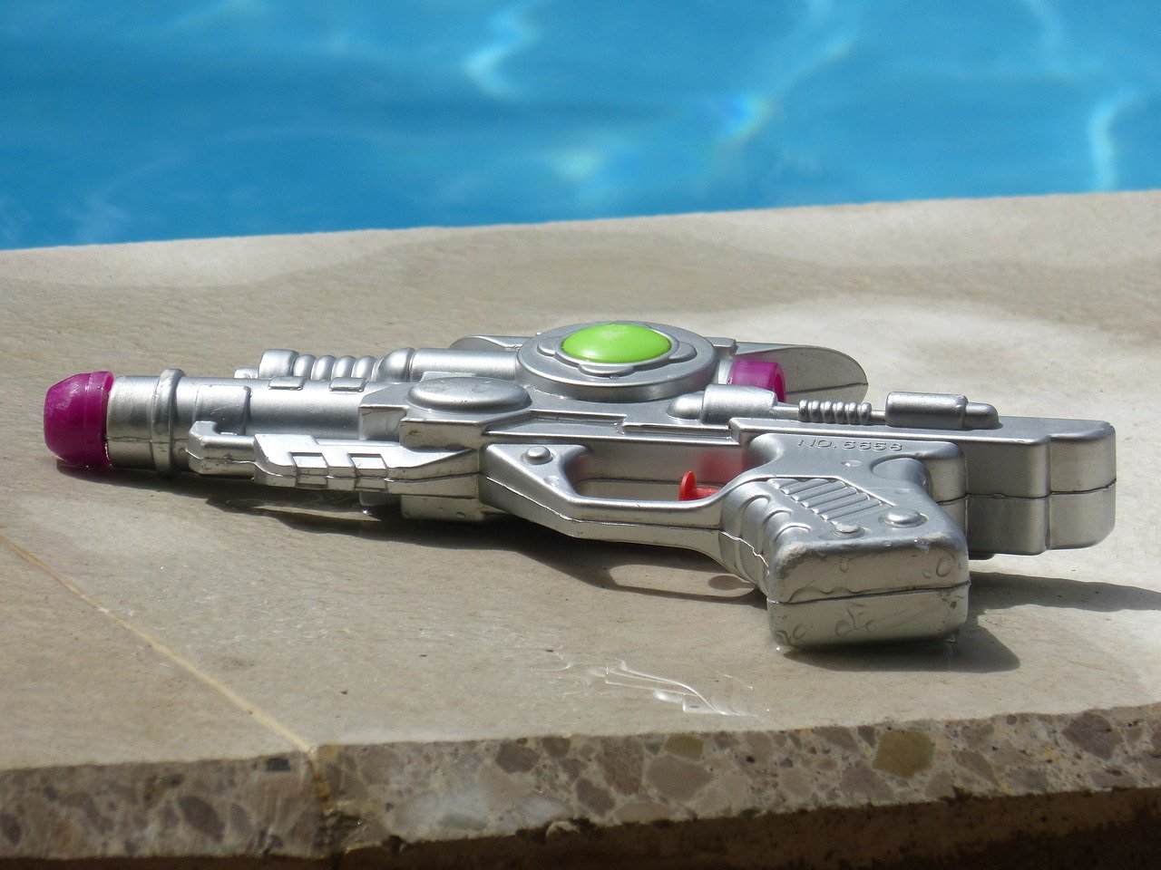 Water gun toy sitting on the edge of a pool