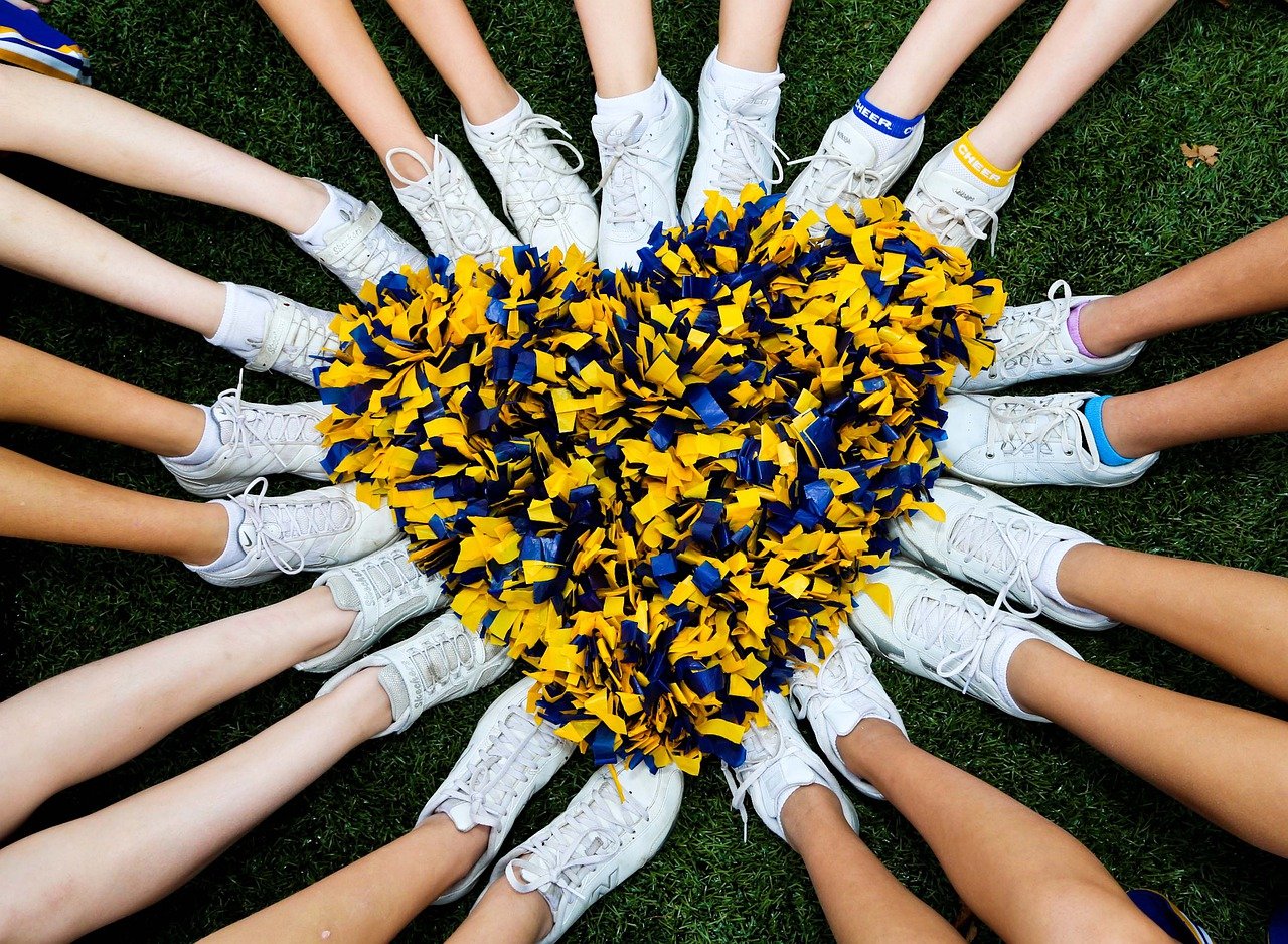 Cheerleaders sitting in a circle with pom poms in the middle