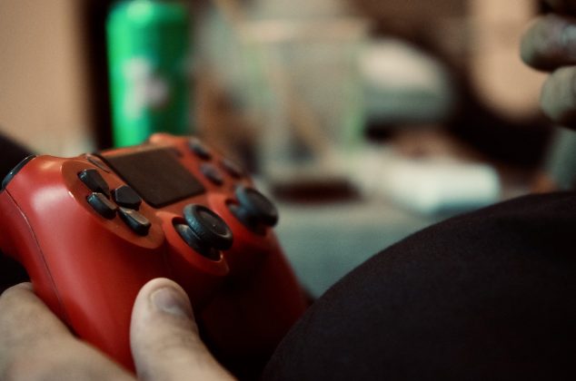 Man's hand holding a red video game controller