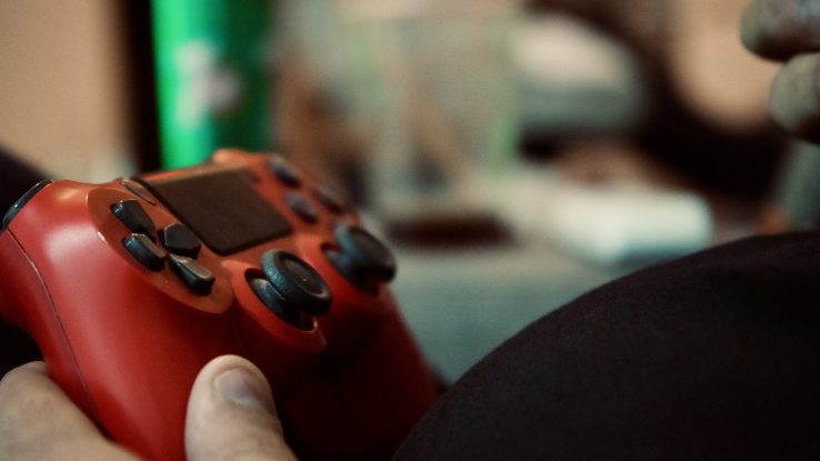 Man's hand holding a red video game controller