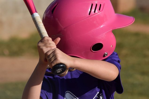 Young athlete wearing a purple team shirt and pink helmet