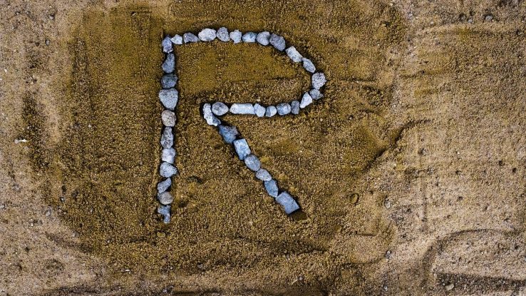 Letter "R" drawn in rocks on sand