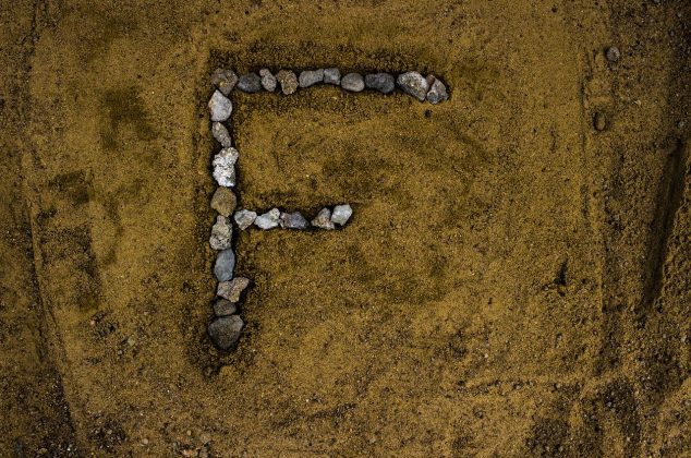 Letter F drawn in rocks on the sand