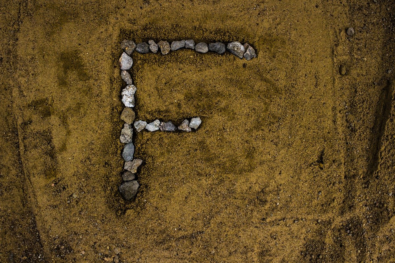 Letter F drawn in rocks on the sand