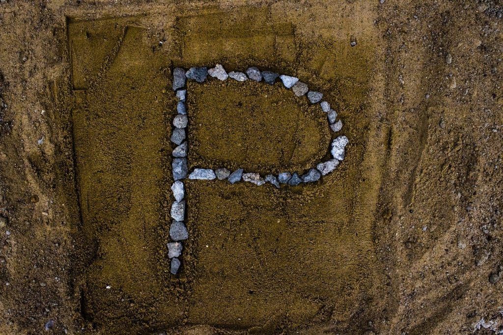 Letter "P" drawn with rocks in sand