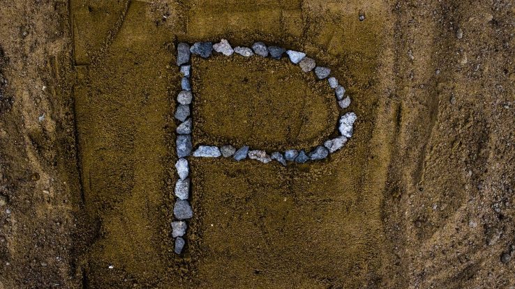 Letter "P" drawn with rocks in sand