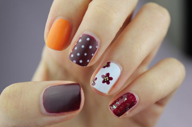 Woman's hand with red, white, and orange nail art