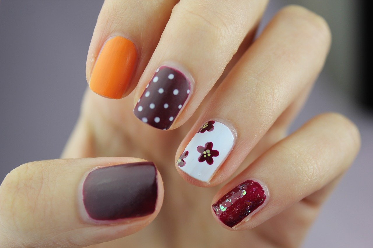 Woman's hand with red, white, and orange nail art