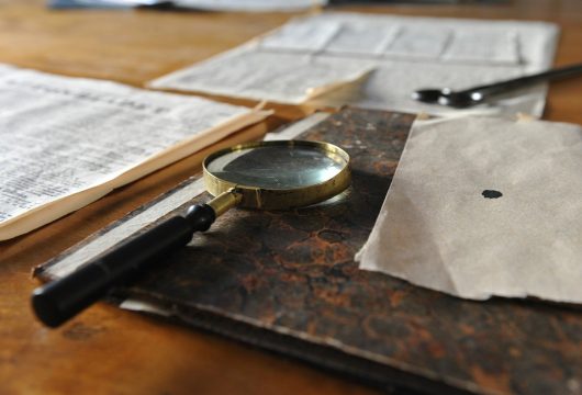 Detective's magnifying glass and documents resting on a desk