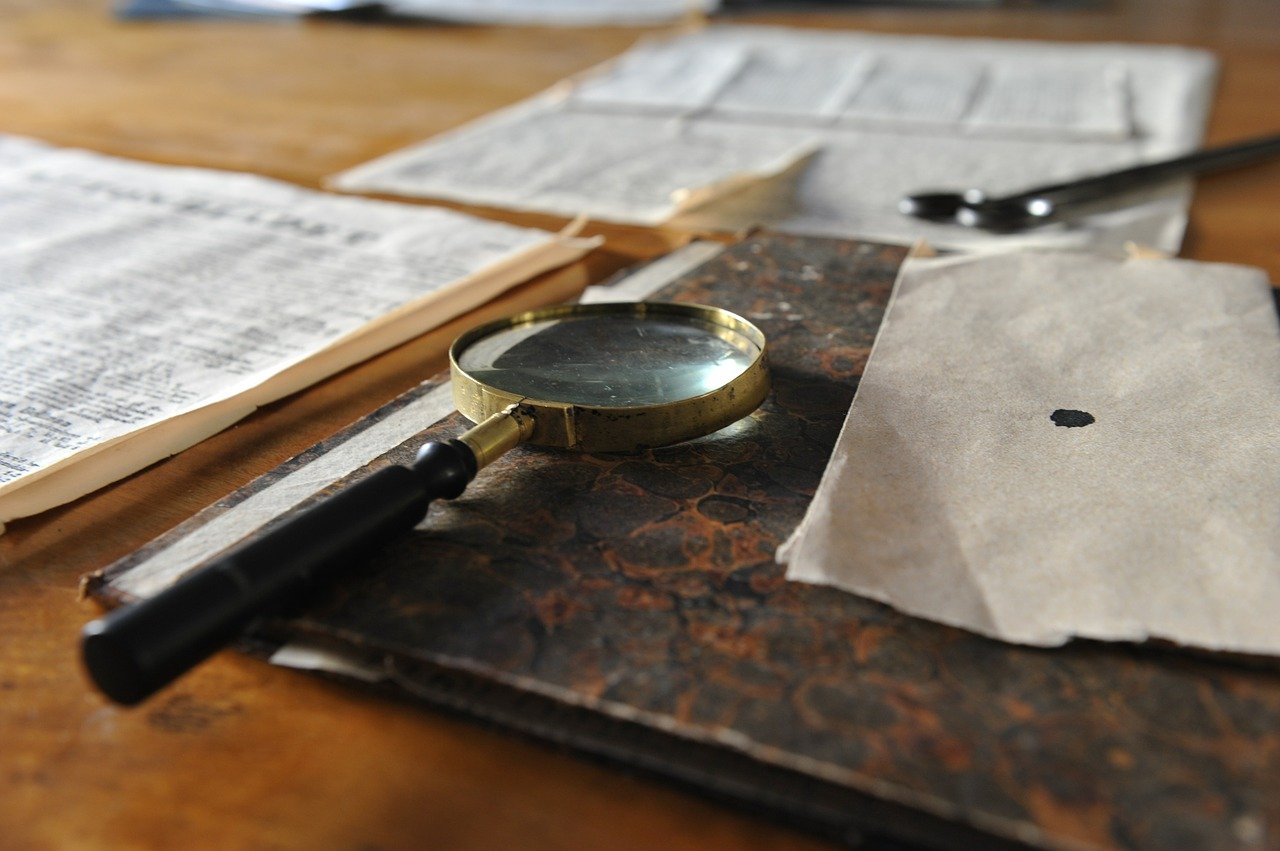 Detective's magnifying glass and documents resting on a desk