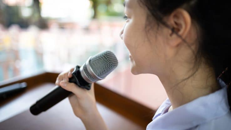 Child speaking into microphone at spelling bee event