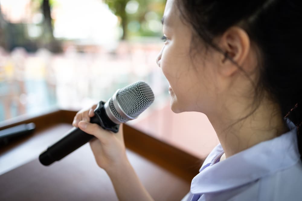 Child speaking into microphone at spelling bee event