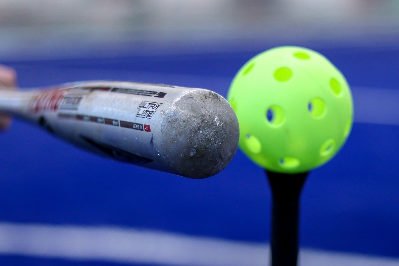 Silver bat hitting a green wiffle ball