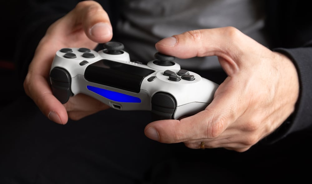 Man's hands holding a PlayStation controller playing Persona 5